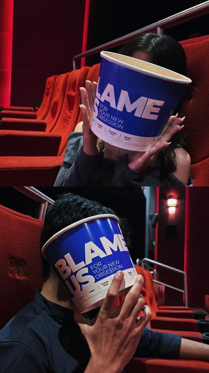 A couple hiding behind popcorn buckets at a cinema