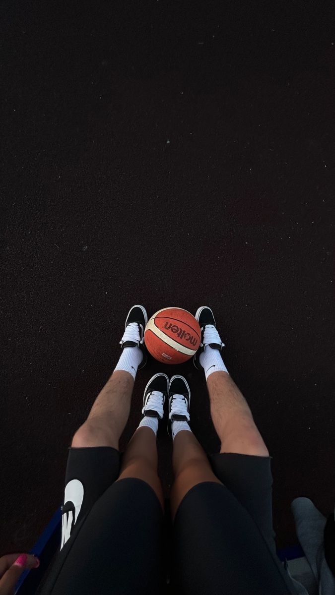 Two pairs of matching shoes with a basketball between them