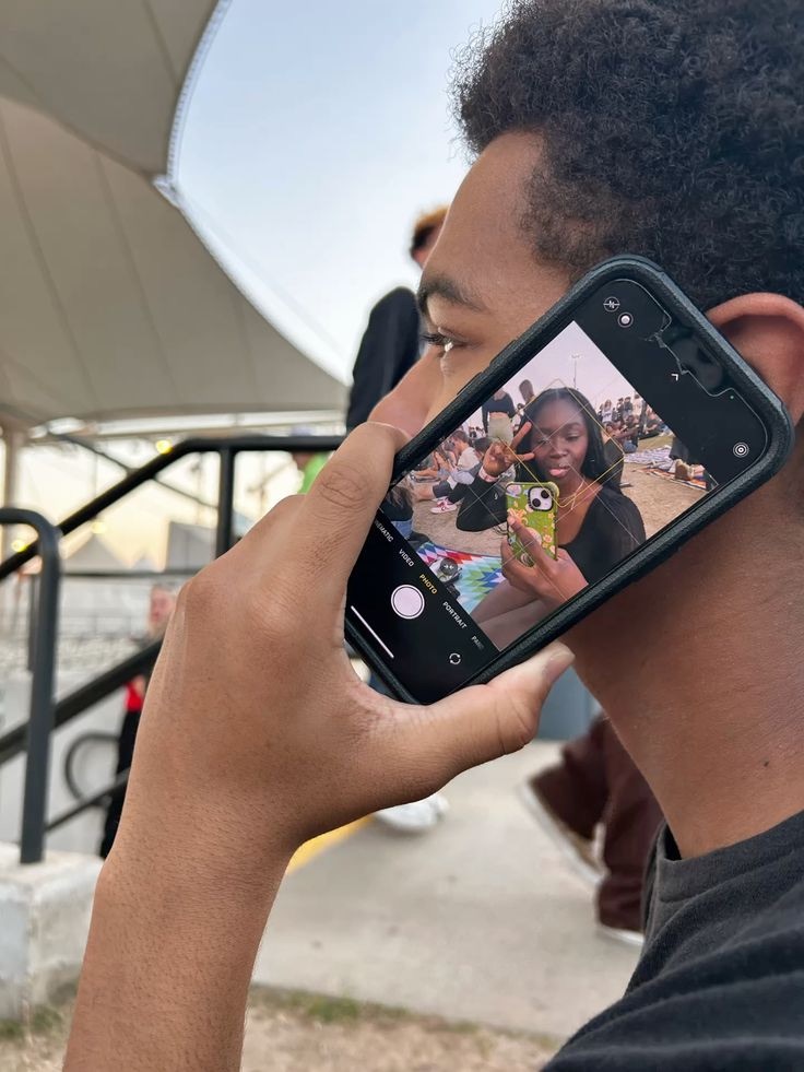 A person holding a phone camera to their ear while photographing a friend